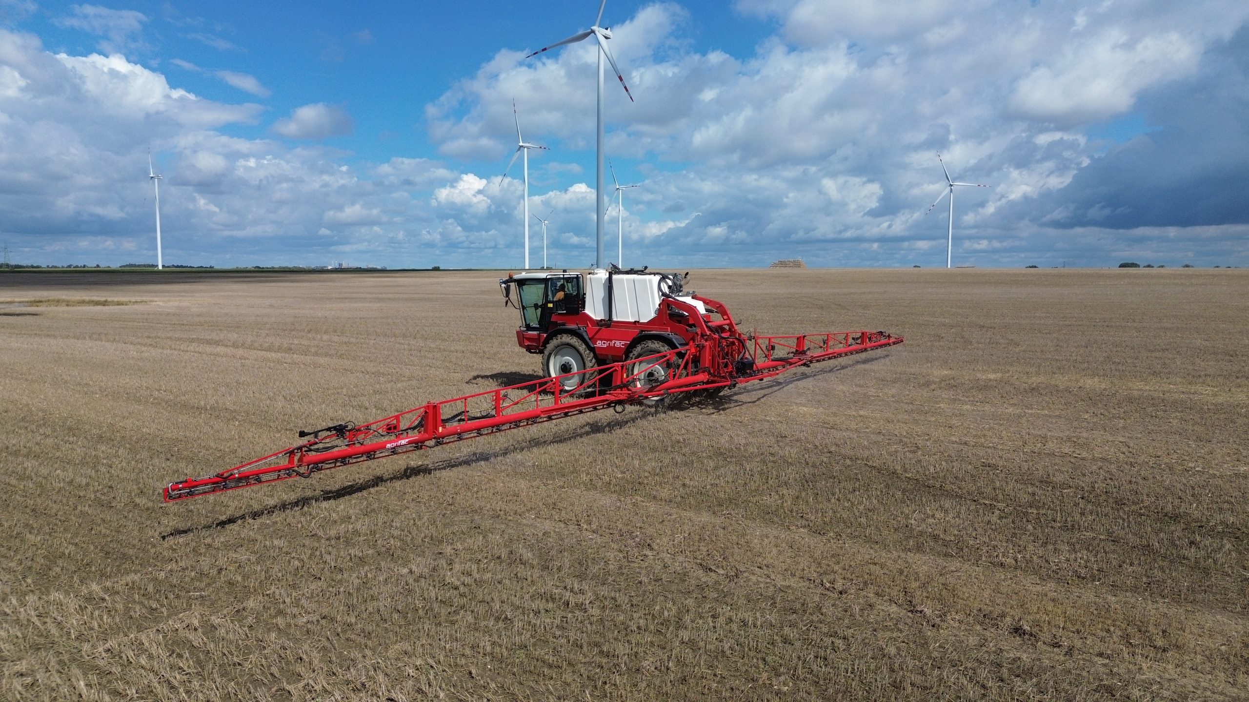 Opryskiwacz samojezdny Agrifac na polu z wiatrakami